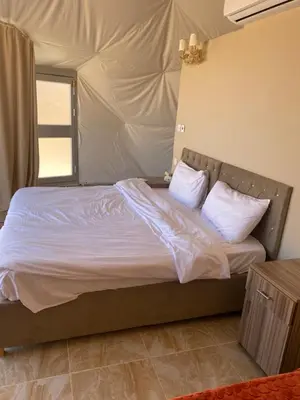 a bedroom with a bed with white sheets and pillows at Aurora Luxury Wadi Rum in Wadi Rum