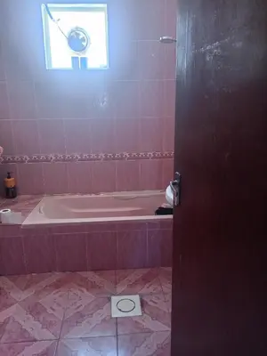 a pink bathroom with a tub and a window at Sky apartment in Amman