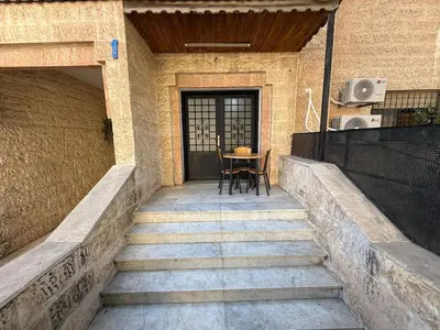 a porch with stairs leading to a door with a table at 2BR Apartment in Tlaa Al Ali, Parking, AC, WIFI in Amman
