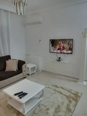 a living room with a couch and a tv on the wall at Two-Bedroom Apartment in Swefieh in Amman