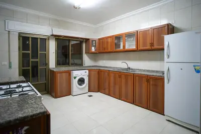 a kitchen with wooden cabinets and a washer and dryer at الوجيه للشقق الفندقية in Amman
