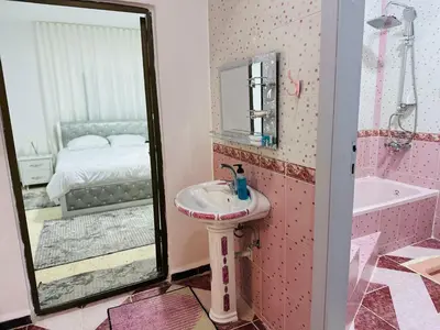 a pink bathroom with a sink and a mirror at شقة مفروشة واسعة وهادئة in Umm Juraysāt