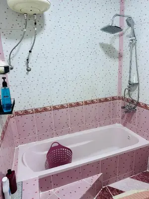 a pink bathroom with a tub and a shower at شقة مفروشة واسعة وهادئة in Umm Juraysāt