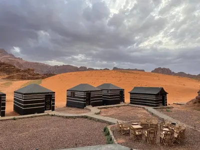a group of huts in the desert with tables and chairs at Red Dunes Wadi Rum Camp in Wadi Rum