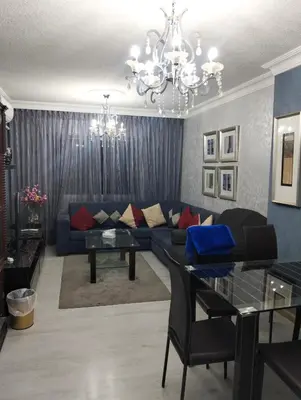a living room with a blue couch and a chandelier at عمان in Amman