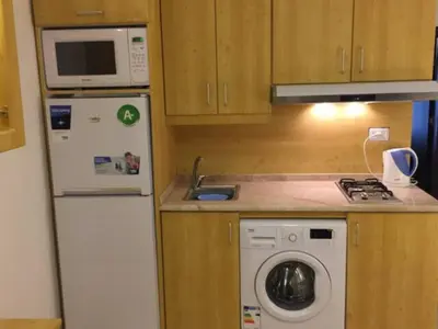 a small kitchen with a refrigerator and a microwave at Ammoun Luxury Apartments 1 in Amman