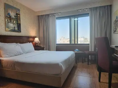 a hotel room with a bed and a desk and a window at Petra Breeze in Wadi Musa