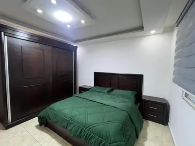 a bedroom with a green bed and a wooden door at شقه مفروشه in Amman