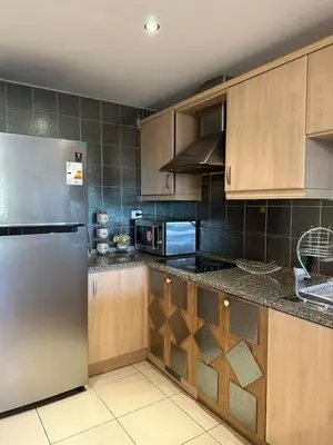 a kitchen with wooden cabinets and a stainless steel refrigerator at Two Bed rooms apartment in Talabay Aqaba Jordan in Aqaba