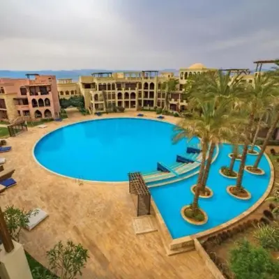 a large swimming pool with palm trees and buildings at Two Bed rooms apartment in Talabay Aqaba Jordan in Aqaba
