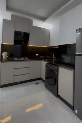a kitchen with white cabinets and a black dishwasher at Luxury furnished apartment in Irbid