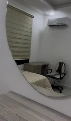 a mirror reflecting a bedroom with a desk and a chair at Luxury furnished apartment in Irbid