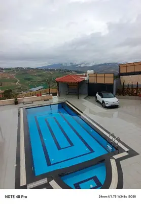 a swimming pool on top of a building with a car at panorama tal elroman chalet in Tal‘at ar Ruzz