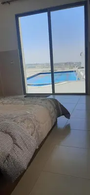 a bedroom with a bed and a view of a pool at panorama tal elroman chalet in Tal‘at ar Ruzz