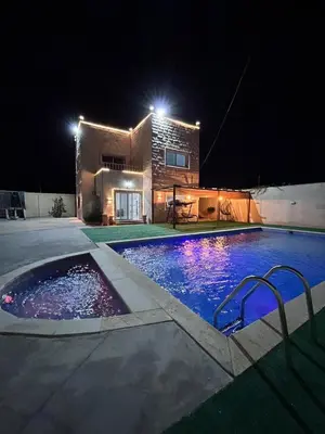 a swimming pool at night with a building in the background at Entire Home Near Deadsea & Baptism Site Pool, Garden, BBQ, Great Price in Shūnat Nimrīn