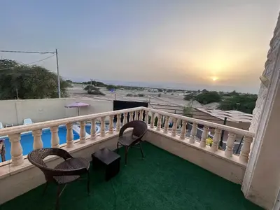 a balcony with chairs and a view of the ocean at Entire Home Near Deadsea & Baptism Site Pool, Garden, BBQ, Great Price in Shūnat Nimrīn