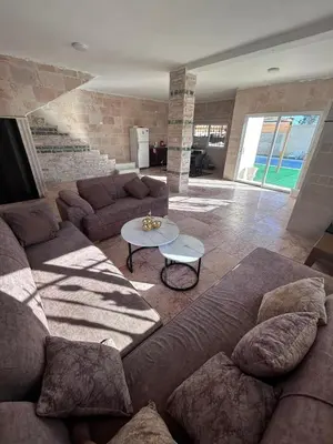 a living room with a couch and a table at Entire Home Near Deadsea & Baptism Site Pool, Garden, BBQ, Great Price in Shūnat Nimrīn