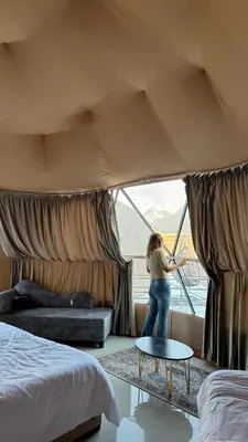 a woman standing in front of a window in a hotel room at Rum Rhal Luxury Camp in Aqaba