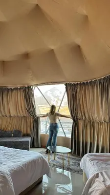 a woman standing in a bedroom looking out the window at Rum Rhal Luxury Camp in Aqaba