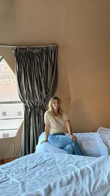 a woman sitting on a bed next to a window at Rum Rhal Luxury Camp in Aqaba