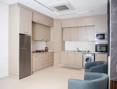 a kitchen with white cabinets and a washer and dryer at The Boulevard Residences in Amman