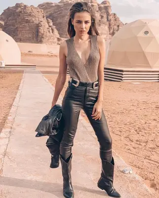 a woman wearing leather pants and boots in the desert at RUM Bubble lUXURY CAMP in Disah