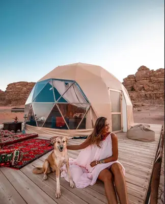 a woman sitting on a dock with a dog in front of a tent at RUM Bubble lUXURY CAMP in Disah