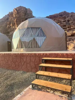 a large dome tent with a wooden bench in front at Suleman Camp in Wadi Rum