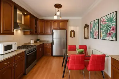 a kitchen with a stainless steel refrigerator and red chairs at The Central Family Apartment in Amman