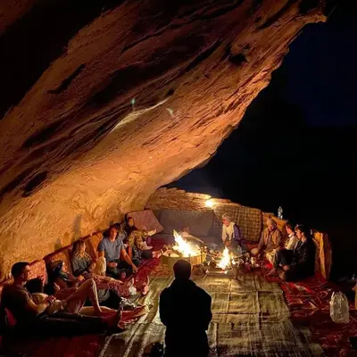 a group of people sitting around a fire in a cave at Camp in the natural reserve & tours in Aqaba