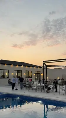 a group of people standing next to a swimming pool at Olive tree chalet and farm -مزرعه و شاليه شجره الزيتون