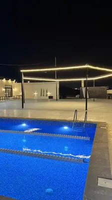 a large swimming pool at night with at Olive tree chalet and farm -مزرعه و شاليه شجره الزيتون