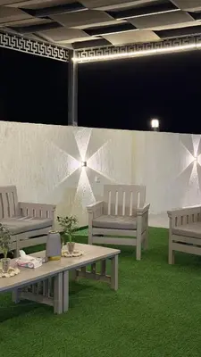 a room with three benches and a table and grass at olive tree farm and chalet - مزرعه و شاليه شجره الزيتون
