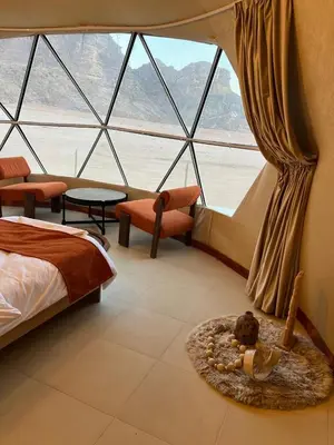 a bedroom with a bed and a large window at Wadi rum Jad luxury camp in Wadi Rum