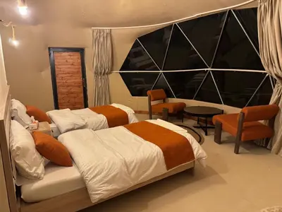 a bedroom with two beds and a table and chairs at Wadi rum Jad luxury camp in Wadi Rum