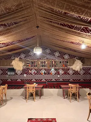 a room with tables and chairs and a ceiling at Wadi rum Jad luxury camp in Wadi Rum