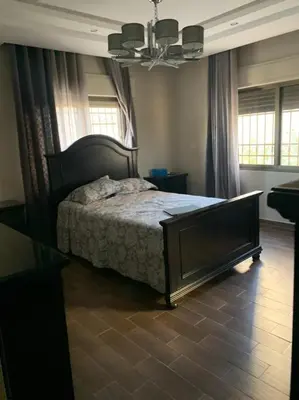 a bedroom with a bed and a table and windows at Luxurious 5 bedroom Furnished Villa superb locationفيلا فخمه in Amman