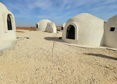 a group of white domed buildings in the desert at Tootya camp
