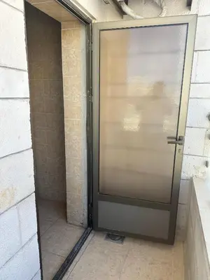 a metal door in a bathroom with a brick wall at الجبيهة 2 نوم aljubiha apartment in Amman