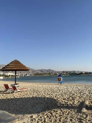 two chairs and an umbrella on a beach at Ayla-Azure in Aqaba