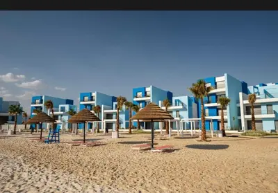a beach with chairs and umbrellas and a building at شقه شاطئيه in Aqaba