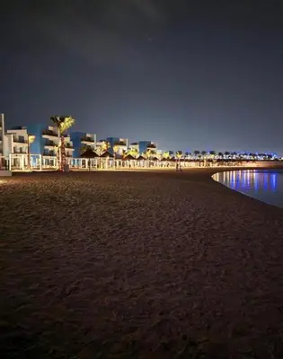 a view of a beach at night with buildings at شقه شاطئيه in Aqaba