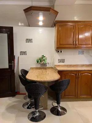 a kitchen with a table and some black chairs at Shmeisani Cozy Apartment in Amman