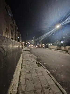 an empty city street at night with a street light at الشهم 10 in Irbid
