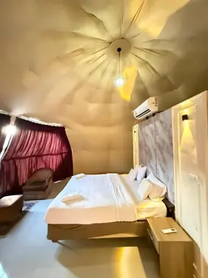a bedroom with a bed with a ceiling with a fan at Nala Luxury Camp & Bubbles Hotel in Wadi Rum