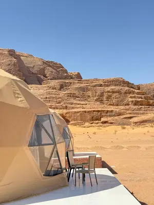a tent with two chairs and a table in the desert at Nala Luxury Camp & Bubbles Hotel in Wadi Rum
