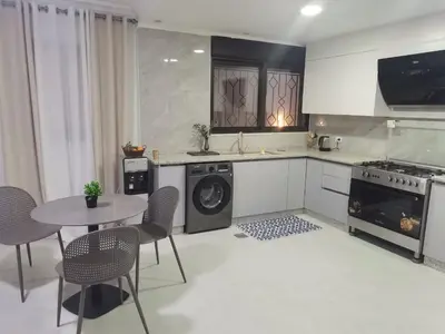 a kitchen with a washing machine and a table with chairs at 2 Master Bedroom Deluxe Apartment Queen Alia Airport Families Women ONLY in Amman