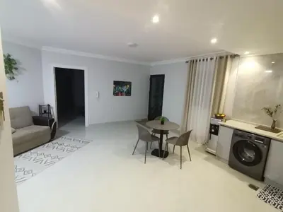 a living room with a table and a couch and a kitchen at 2 Master Bedroom Deluxe Apartment Queen Alia Airport Families Women ONLY in Amman