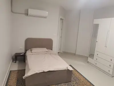 a white room with a bed and a mirror at 2 Master Bedroom Deluxe Apartment Queen Alia Airport Families Women ONLY in Amman