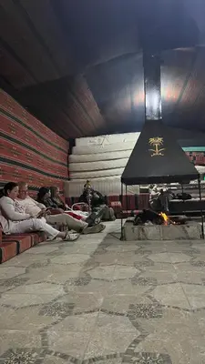 a group of people sitting around a fire in a room at wadi rum planet camp in Disah